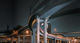 A night view of a city scene with multiple highway overpasses overlapping. 