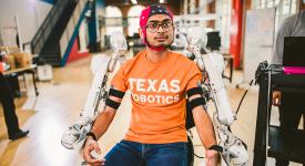 Student working on robotic assistive arms, wearing he device.